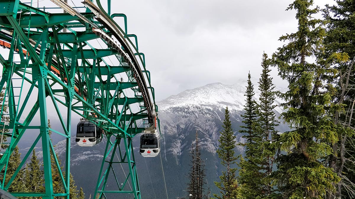 Guide To The Banff Gondola upper terminal looking at the Gondola cars and Rundle Mountain range